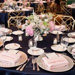 Table set for a Quinceanera formal dinner with navy blue and blush theme, adorned with pink and white flowers