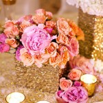A beautiful Quinceanera table centerpiece with rose floral design. The table is topped with gold vases filled with flowers.