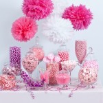 A table topped with lots of different types of candy and cut flowers