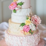 A three-tiered Quinceanera cake with pink and yellow flowers