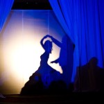 A silhouette of a woman dancing on stage in a light cobalt blue setting for a Quinceanera celebration.