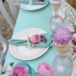 Quinceanera, a lavender and aqua table set with plates and flowers on it