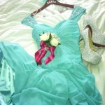 A Quinceanera dress, shoes, and mythical creature dress are laid out on a bed