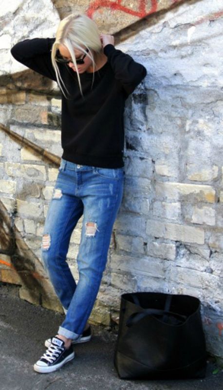 A woman wearing jeans and a Quinceanera, leaning against a brick wall with her hands on her head.