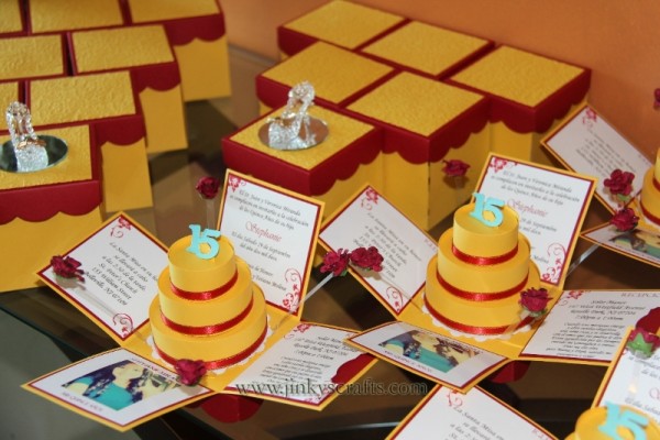 A Quinceanera Beauty and the Beast themed wedding invitation on a table with lots of cards and a cake