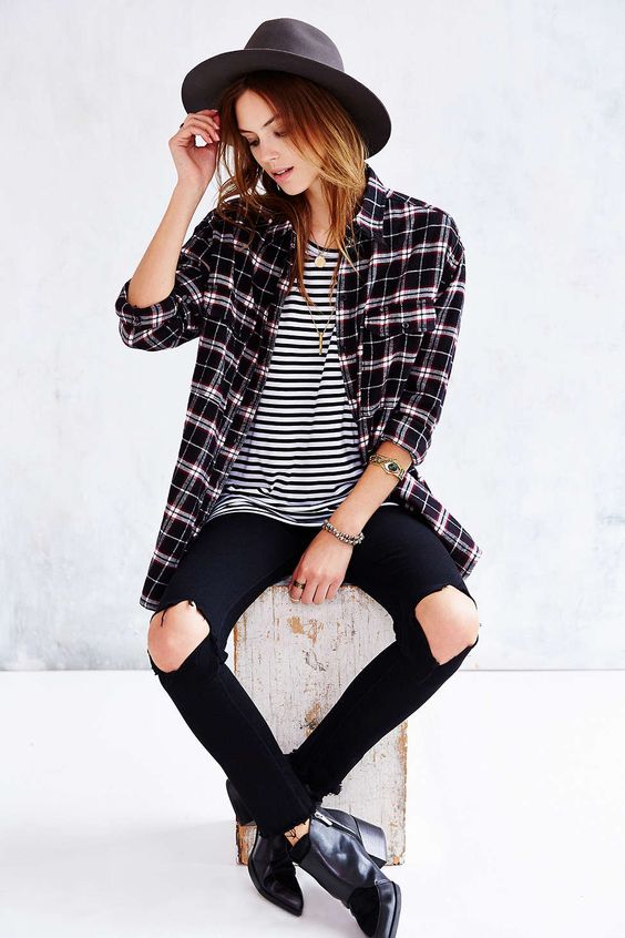 A stylish woman in hipster outfits sitting on top of a wooden block, wearing a hat at a Quinceanera event.