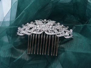 A Quinceanera themed image featuring a headpiece Jewellery, a silver hair comb against a green cloth.