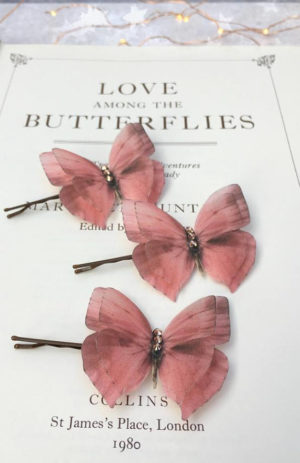 A close up image of three hair pins with flowers on them, depicting a butterfly Quinceañera theme.