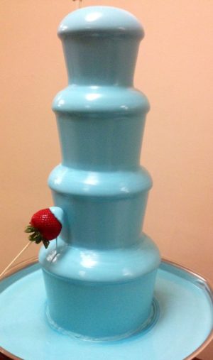 Quinceanera-themed image of a blue chocolate fountain with a strawberry on top