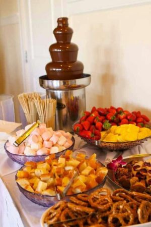 An image of a Quinceanera celebration featuring a buffet table with a chocolate fountain, surrounded by various chocolate treats and goodies.