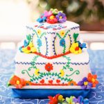 A three-tiered cake with flowers on a table, decorated in a Quinceanera theme, showcasing Mexican cuisine