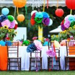 A colorful Quinceañera balloon with a table adorned with a bunch of colorful paper flowers