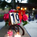 A table decorated with cut flowers and candles for a Quinceañera celebration, with a table number on it.