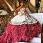 Gorgeous Quinceañera dresses, featuring a woman in a stunning pink and white gown, standing gracefully on a grand staircase