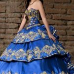 A woman in a blue and gold quinceanera dress posing for a picture with charro Quinceañera dresses