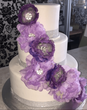 A three-tiered Quinceanera cake with purple flowers