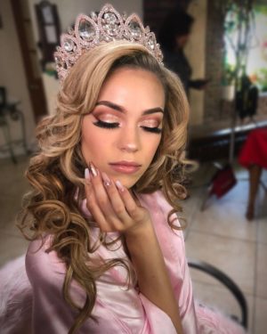 Quinceanera image: a woman in a pink dress with a tia on her head, showcasing the 2023 Quinceanera makeup