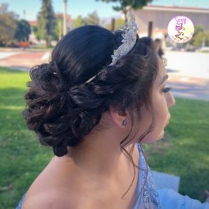 A woman in a blue Quinceanera dress with a tiable on her head, also wearing a headpiece Chignon
