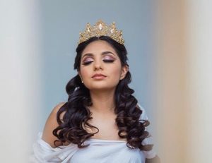 A woman with long hair wearing a white dress and a crown on her head for a Quinceanera celebration