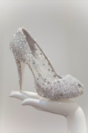 Quinceanera silver glittered high-heeled shoe on a white hand