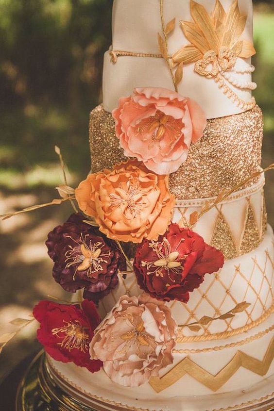 Quinceanera theme image of a three-tiered cake with flowers on top, in rose gold, gold, and burgundy