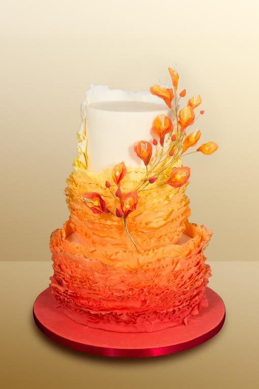 A Quinceanera cake with a three tiered buttercream frosting decorated with orange flowers on top