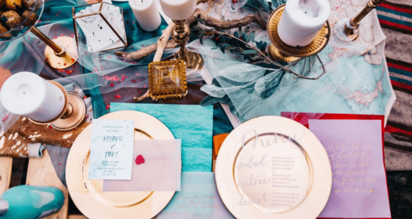 A Quinceanera celebration with orange and turquoise colors. A beautifully decorated table with plates and silverware.