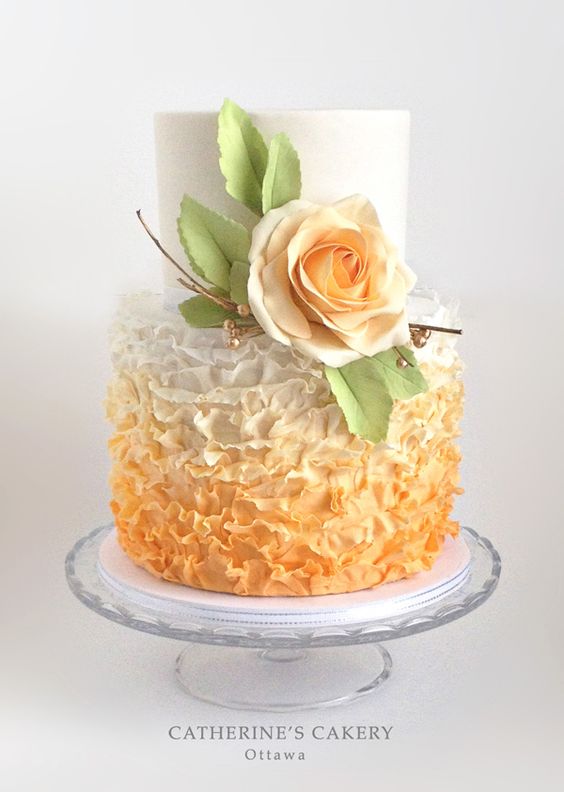 A Quinceanera cake with buttercream frosting, featuring a white and orange design and topped with a rose