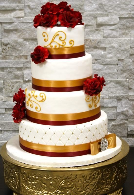 A three-tiered Quinceanera cake with red flowers and a beautiful red and gold color scheme.