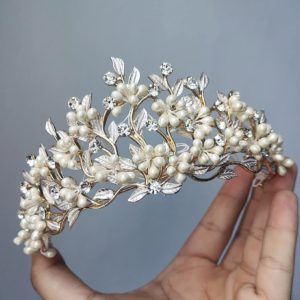A Quinceanera headpiece jewellery with pearls, leaves, and a hand holding a tia