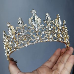 A hand holding a gold and crystal tiara with a crown Tiara for a Quinceanera celebration