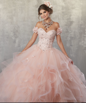 A woman in a pink gown for a Quinceanera, posing for a picture