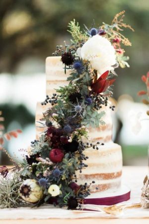 Quinceanera color ideas, a Quinceanera cake with flowers and greenery on a table