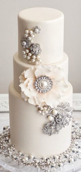 Quinceanera cakes with diamonds, pearls, and flowers, including a cupcake and a white cake