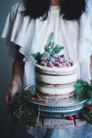 A woman holding a chocolate cake decorated with frosting and cranberries for a Quinceanera celebration.