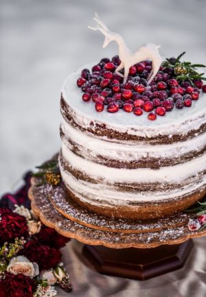 A Quinceanera cake with frosting and berries on top, surrounded by a Quinceanera invitation
