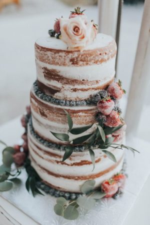 A summer Quinceanera naked cake with flowers on top of it