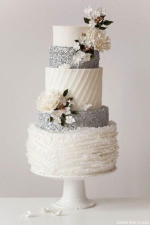 A three tiered Quinceanera cake decorated with flowers on top in a winter theme
