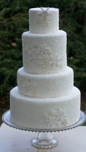 A beautiful three-tiered white wedding cake with icing on a table, perfect for a Quinceanera celebration in a winter wonderland theme.