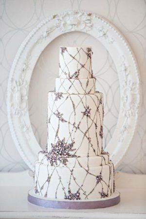 A three-tiered Quinceanera cake with a purple ribbon