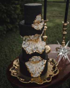 A black and gold Quinceanera cake sitting on top of a table
