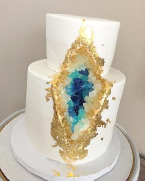Quinceanera cake - A white and gold cake with a slice of blue and gold on top