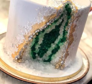 A Quinceanera cake, with green and white frosting, displayed on a plate