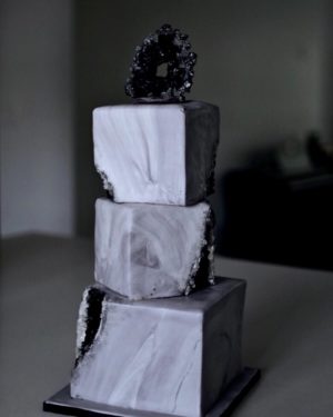 A black and gold quinceanera cake sitting on top of a table