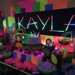 A Quinceanera party with a table topped with lots of candy and candy bars, incorporating glow in the dark kids party ideas