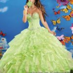 A woman in a green Quinceanera gown is posing for a picture.