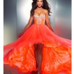 A woman in an orange dress posing for a picture in neon glow in the dark Quinceañera dresses