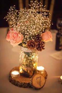 A rustic Quinceanera centerpiece idea featuring a table with a vase filled with flowers and candles