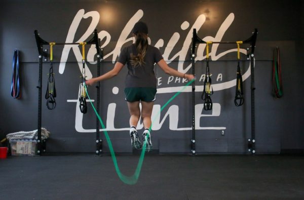 A woman doing a jump rope exercise in a gym, inspiring health training in HD