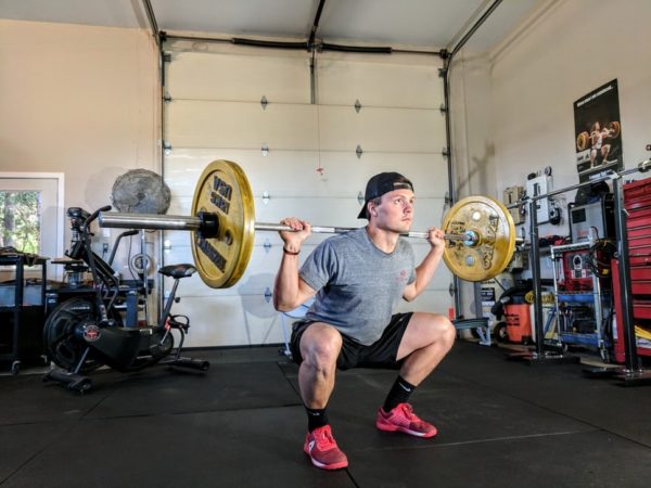 A man squatting with a barbell in a Quinceanera-themed gym